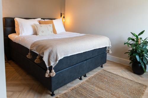 a bedroom with a bed with pillows and a plant at Bed en Baguette in Burgh Haamstede