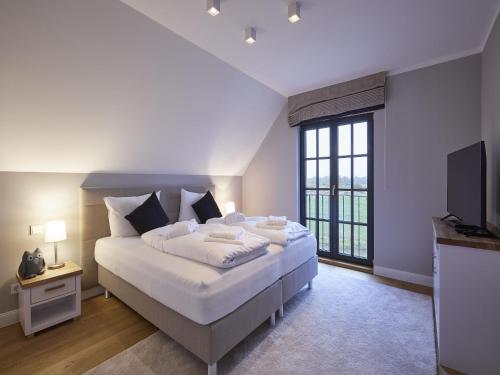 a bedroom with a large bed and a television at Reetland am Meer - Luxus Reetdachvilla mit 3 Schlafzimmern, Sauna und Kamin F11 in Dranske