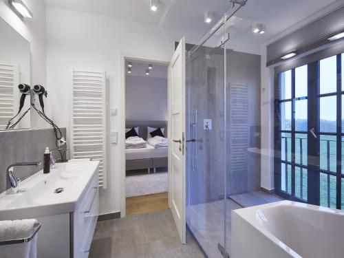 a bathroom with a tub and a sink and a shower at Reetland am Meer - Luxus Reetdachvilla mit 3 Schlafzimmern, Sauna und Kamin F11 in Dranske