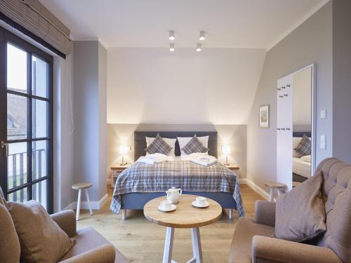Schlafzimmer mit einem Bett, einem Tisch und Stühlen in der Unterkunft Reetland am Meer - Premium Reetdachvilla mit 3 Schlafzimmern, Sauna und Kamin F10 in Dranske