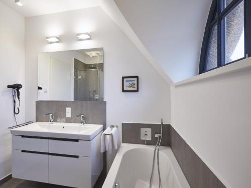a white bathroom with a sink and a bath tub at Reetland am Meer - Premium Reetdachvilla mit 3 Schlafzimmern, Sauna und Kamin F10 in Dranske