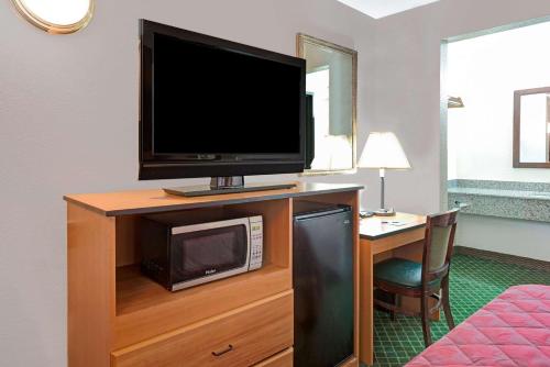 a room with a television and a desk with a microwave at Travelodge by Wyndham Sacramento / Rancho Cordova in Sacramento