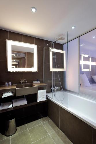 a bathroom with a sink and a tub and a mirror at Novotel Avignon Centre in Avignon