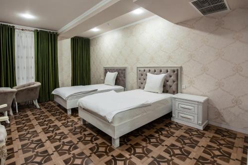 two beds in a room with green curtains at OydinPlaza Hotel in Namangan