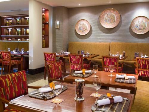 a restaurant with tables and chairs and plates on the wall at Novotel Semarang in Semarang