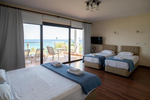 two beds in a room with a view of the ocean at Seafront Protaras Villas in Protaras