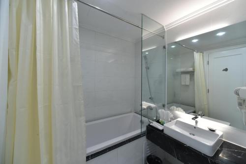 a white bathroom with a sink and a shower at Garco Dragon Hotel 2 in Hanoi