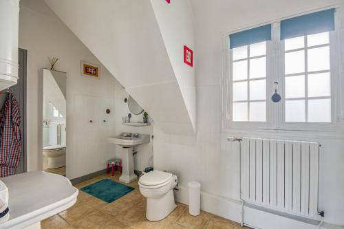 une salle de bain blanche avec des toilettes et un lavabo dans l'établissement Castel Breiz - Maison vue mer, accès plage Fréhel, à Fréhel