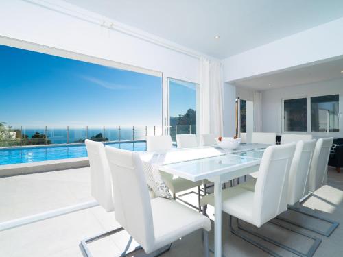 a white dining room with a table and white chairs at Holiday Home Vista al Mar by Interhome in Benitachell