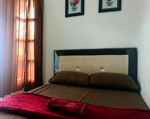 a bed with a red blanket on top of it at EDUTAMA Homestay Syariah in Kediri
