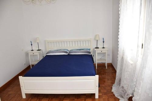 a bedroom with a white bed with blue sheets and two tables at L' incantevole paesaggio della laguna di Murano in Murano