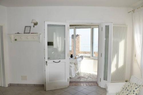 Habitación blanca con una puerta que da a una sala de estar. en L' incantevole paesaggio della laguna di Murano en Murano