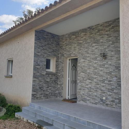 une maison avec un mur en pierre et une porte blanche dans l'établissement Villa Salute 6 pers 5 min plage en voiture, à Porto-Vecchio