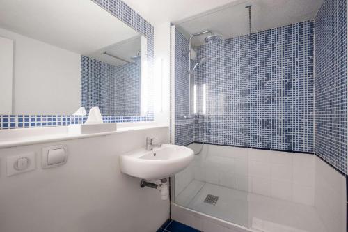 Baño blanco con lavabo y espejo en Comfort Hotel ORLY-RUNGIS en Rungis
