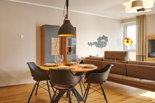 a dining room with a table and chairs and a couch at die Tauplitz Lodges - Adler Auszeit Lodge D6 by AA Holiday Homes in Tauplitz
