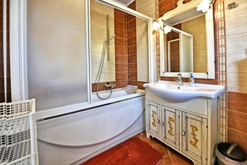 uma casa de banho com uma banheira, um lavatório e um chuveiro em Apartments Laguna em Porec