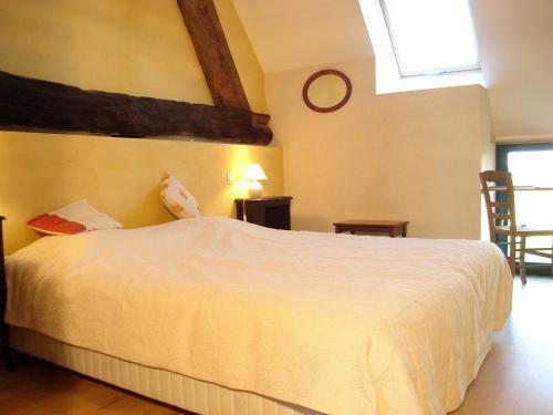 Un dormitorio con una cama blanca y una ventana. en Le Petit Courtoux, en Saint-Germain-en-Coglès