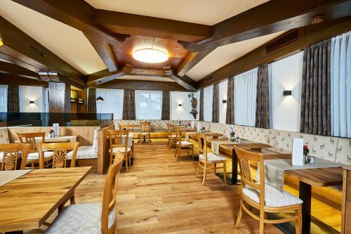 um restaurante com mesas e cadeiras de madeira e janelas em Hotel Rupertihof em Ainring