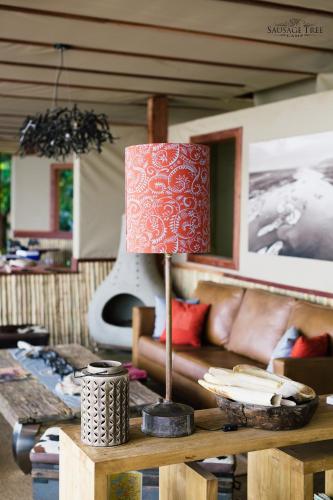 a living room with a table with a lamp on it at Sausage Tree Camp in Jeki