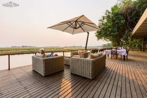 a wooden deck with chairs and an umbrella at Sausage Tree Camp in Jeki
