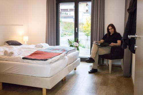 a woman sitting in a chair next to a bed at Appart Gastauer in Sankt Gallenkirch