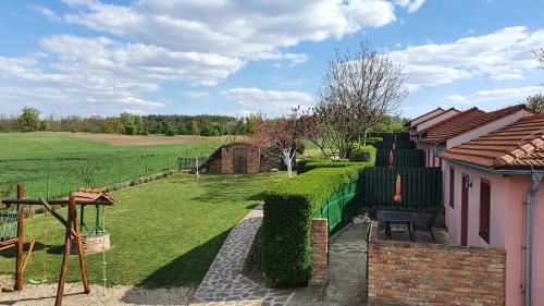 a house with a fence and a yard with a field at Penzion Na Lednické in Hlohovec