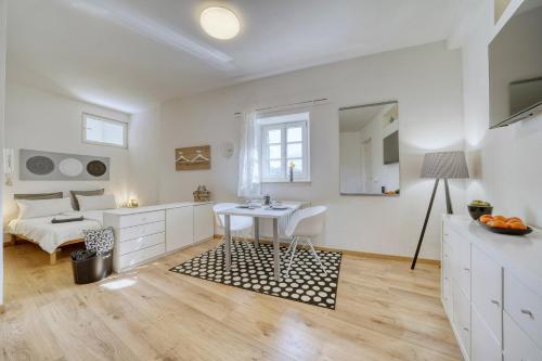 biały pokój ze stołem i łóżkiem w obiekcie Zentral gelegenes Apartment mit Garage und Garten w mieście Caldaro