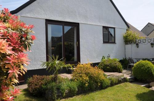 a white house with a large window and plants at Sunny detached bungalow, Nr Looe in Saint Keyne