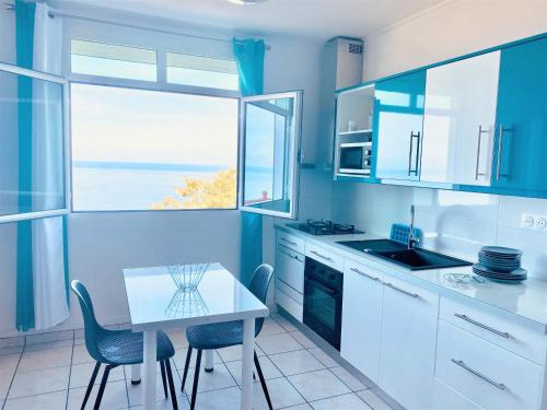 a blue kitchen with a table and chairs and a window at Gîtes Dardanelle in Bouillante