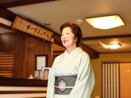 a woman in a kimono standing in a room at Seikiro Ryokan Historical Museum Hotel in Miyazu