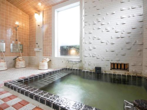 a large pool of water in a bathroom with a window at Seikiro Ryokan Historical Museum Hotel in Miyazu