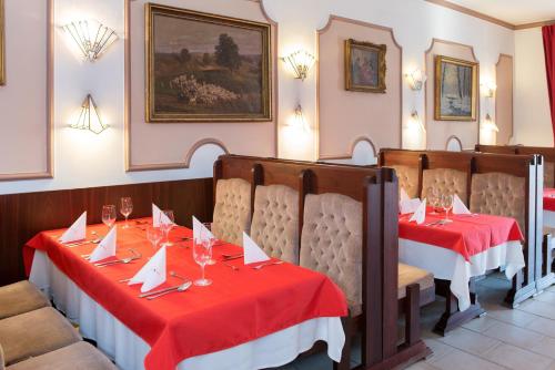 a restaurant with two tables with red table cloth at Hotel Piroska in Bük