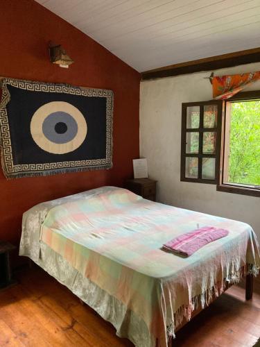 a bedroom with a bed with a painting on the wall at Sítio Macaúbas do Moinho in Alto Paraíso de Goiás