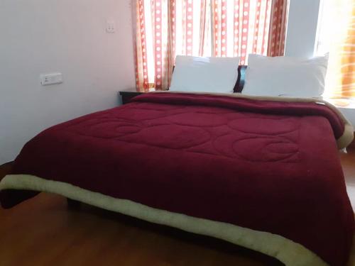 a bedroom with a bed with a red blanket and pillows at Dragon I Resorts in McLeod Ganj