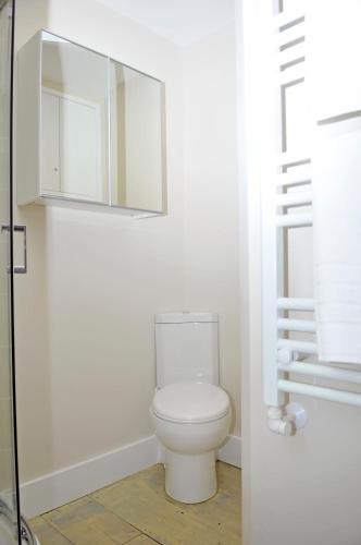 a white bathroom with a toilet and a mirror at Little Lane in Alverstoke