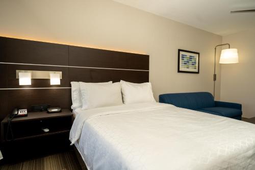 a hotel room with a large bed and a blue chair at Holiday Inn Express & Suites Deer Park by IHG in Deer Park