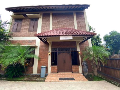 a brick house with a brown door and a fence at Imogen Yogyakarta in Yogyakarta