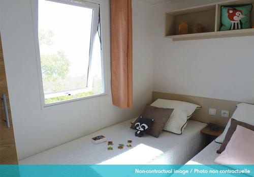 a small bedroom with a bed with a window at Camping Officiel Siblu Les Rives de Condrieu in Condrieu