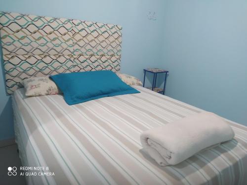 Cantinho da Tia Sandra Suíte 3 في ساو فرانسيسكو دو سول: سرير عليه أغطية بيضاء ومخدات زرقاء