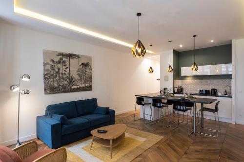 un salon avec un canapé bleu et une cuisine dans l'établissement Le Confident - Grand T2 au coeur de Lyon, à Lyon