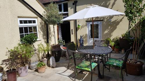 a patio with a table and chairs and an umbrella at The Hanging Gate Coach House in Madeley
