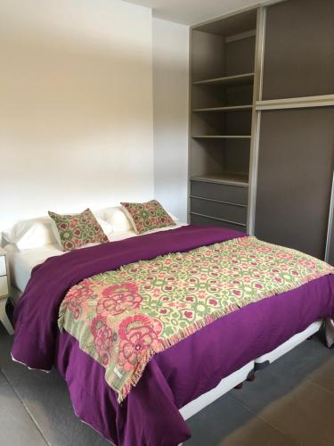 a bedroom with a bed with a purple comforter at Departamento en Villa Allende in Villa Allende