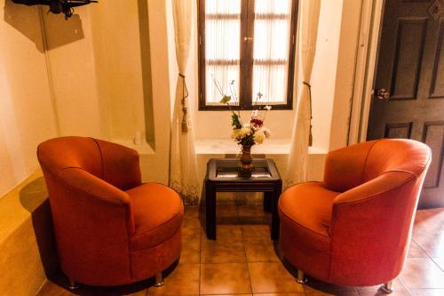duas cadeiras cor-de-laranja sentadas numa sala com uma mesa em Hotel T KON T em Antigua Guatemala