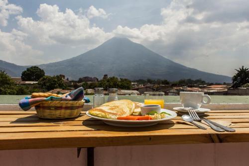 a table with a plate of food with a mountain in the background at Hotel T KON T in Antigua Guatemala