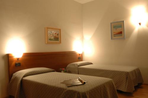a hotel room with two beds and lights on the wall at Hotel San Marco in Prato