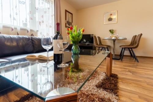 a living room with a glass table and wine glasses at Central Apartment in Donovaly