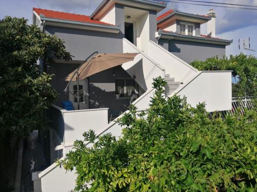 una casa blanca con una sombrilla en las escaleras en Apartment Gloria3, en Marina