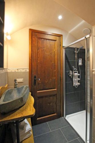 a bathroom with a sink and a shower with a wooden door at Mella Bellagio -La Corte - at the Lake with parking in Bellagio