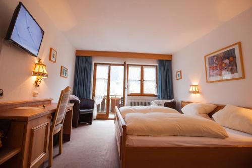 una camera d'albergo con 2 letti e una scrivania di Hotel Pfrontener Hof a Pfronten