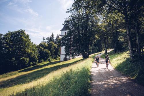 two people riding bikes down a dirt road at Pohorje Village Wellbeing Resort - Forest Hotel Videc in Pohorje